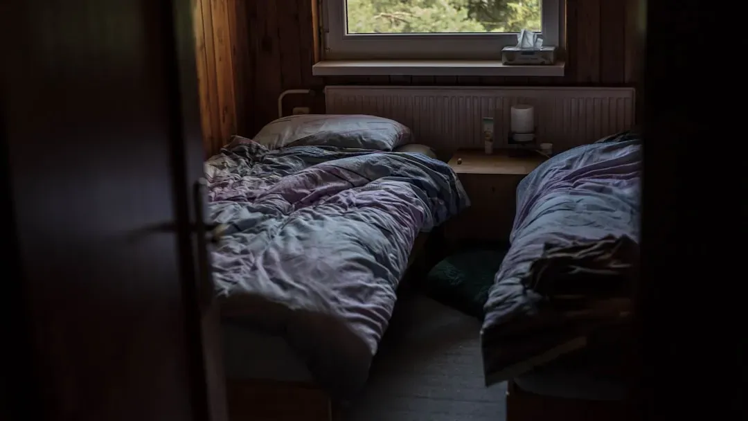 Man sleeping peacefully in dark bedroom demonstrating quality sleep, a key looksmaxxing tip for men's appearance and health.