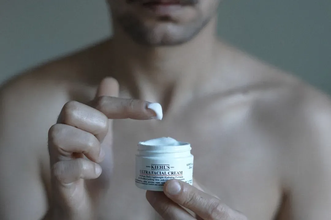Man applying retinoid serum during skincare routine for looksmaxxing, demonstrating effective skincare practices in bright ba