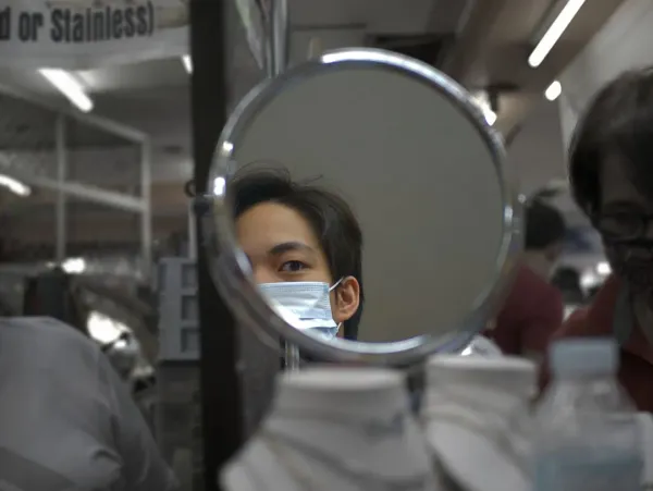 Young man examining his facial features in mirror with thoughtful expression, demonstrating self-assessment in looksmaxxing c